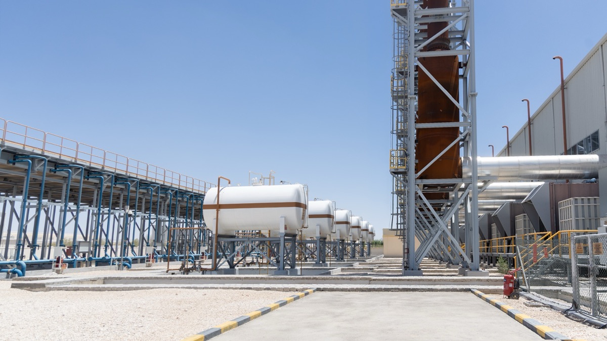 Row of white process gas storage vessels beside a steel structure